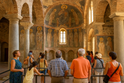 Mensen van verschillende leeftijden bezichtigen oude fresco’s en stenen bogen in een Byzantijnse kerk