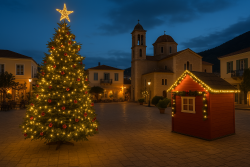 Verlichte kerstboom en decoraties op een dorpsplein in de Peloponnesos met kerk op de achtergrond
