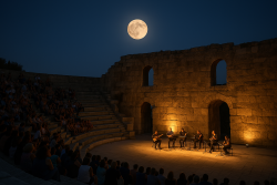 Muzikanten spelen in een verlicht Grieks theater onder volle maan met publiek op stenen treden