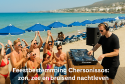 DJ draait muziek tijdens een strandfeest in Chersonissos, omringd door feestende jongeren in badkleding, met blauwe parasols en turquoise zee op de achtergrond.